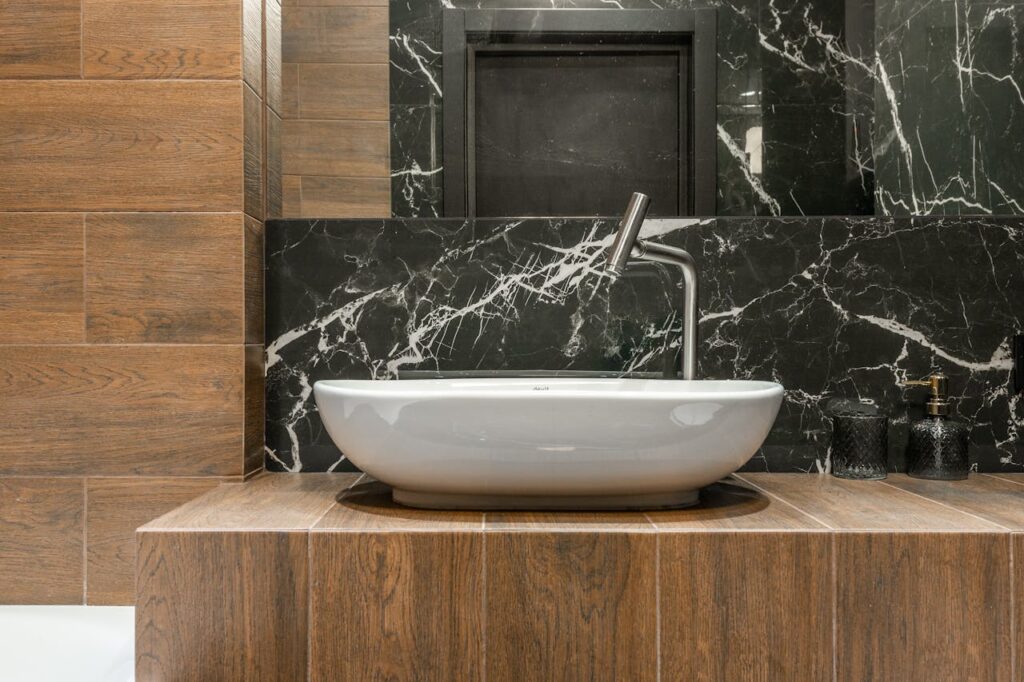 Elegant bathroom with a modern washbasin, wood paneling, and black marble decor.